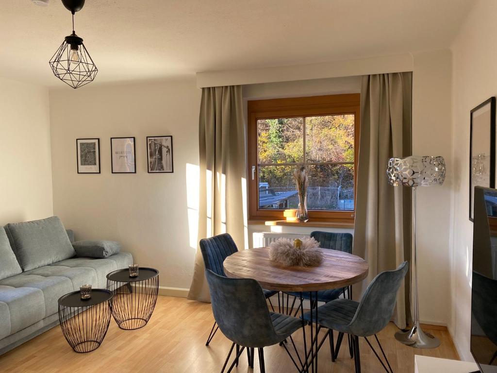 een woonkamer met een tafel en stoelen en een bank bij Gemütliche Wohnung mit Gartenblick in Innsbruck