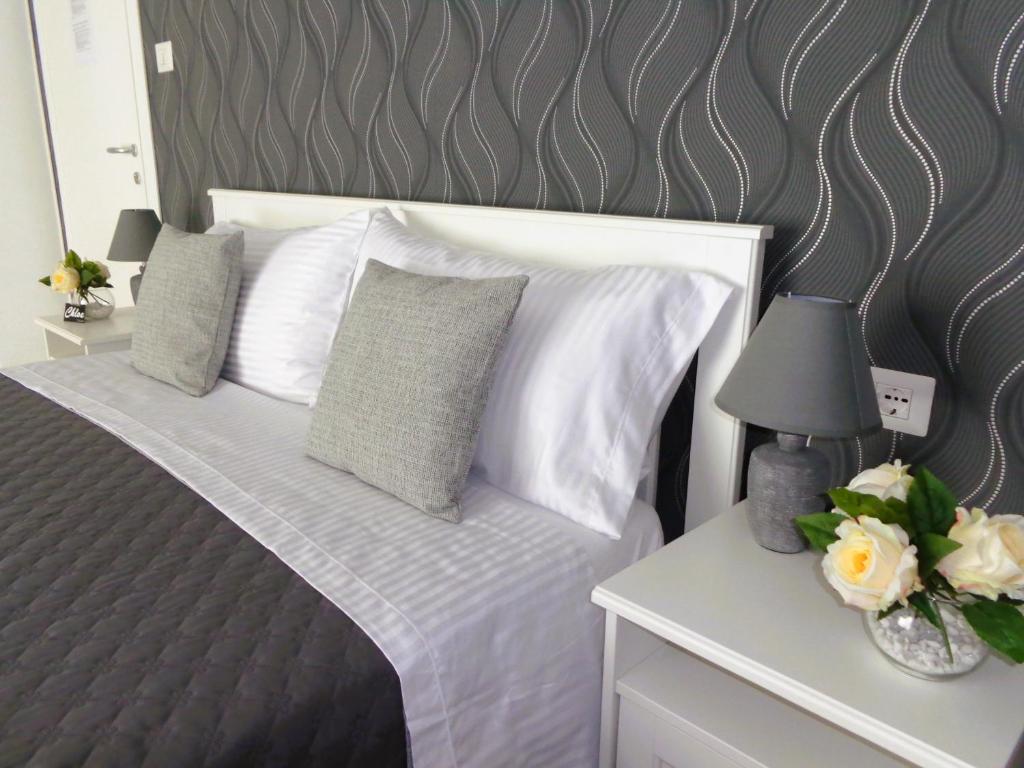Cama con almohadas blancas y mesa con lámpara en Chloe's Rooms en Cagliari