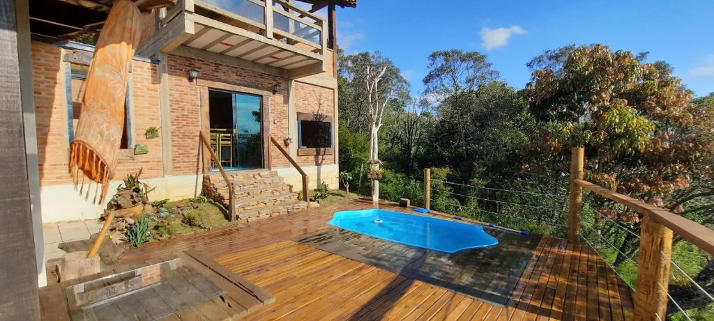 a house with a wooden deck with a blue swimming pool at Casa Refúgio da Paz - 2 quartos, 10 pessoas in Conceição da Ibitipoca