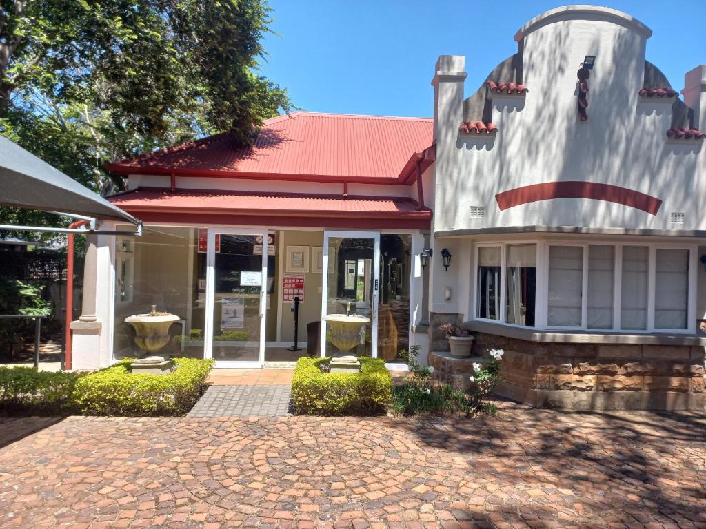a house with a red roof and a brick driveway at Liza's Cottage Guesthouse in Pretoria