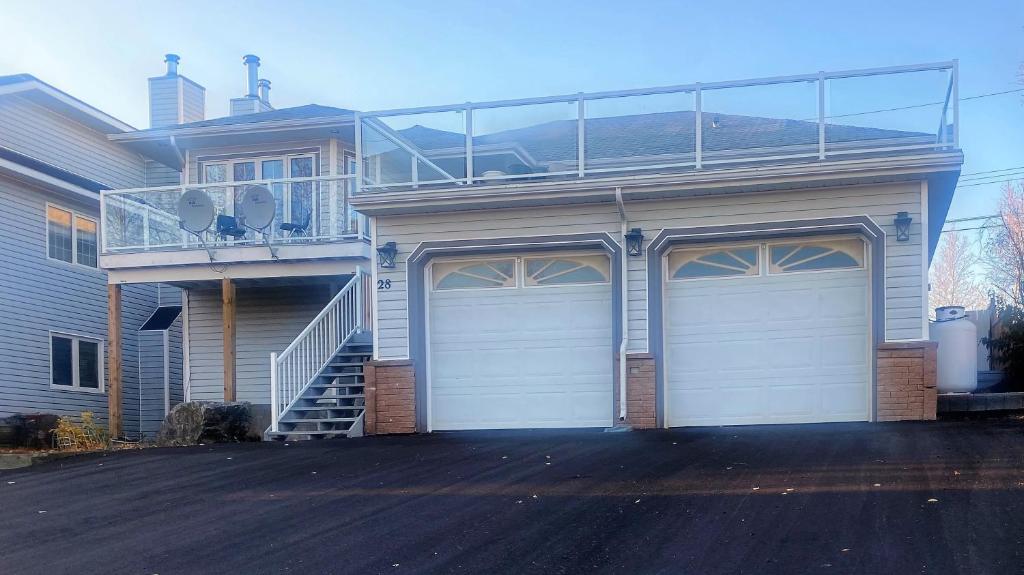 a house with two garage doors and a balcony at Yellowknife Bed and Breakfast in Yellowknife