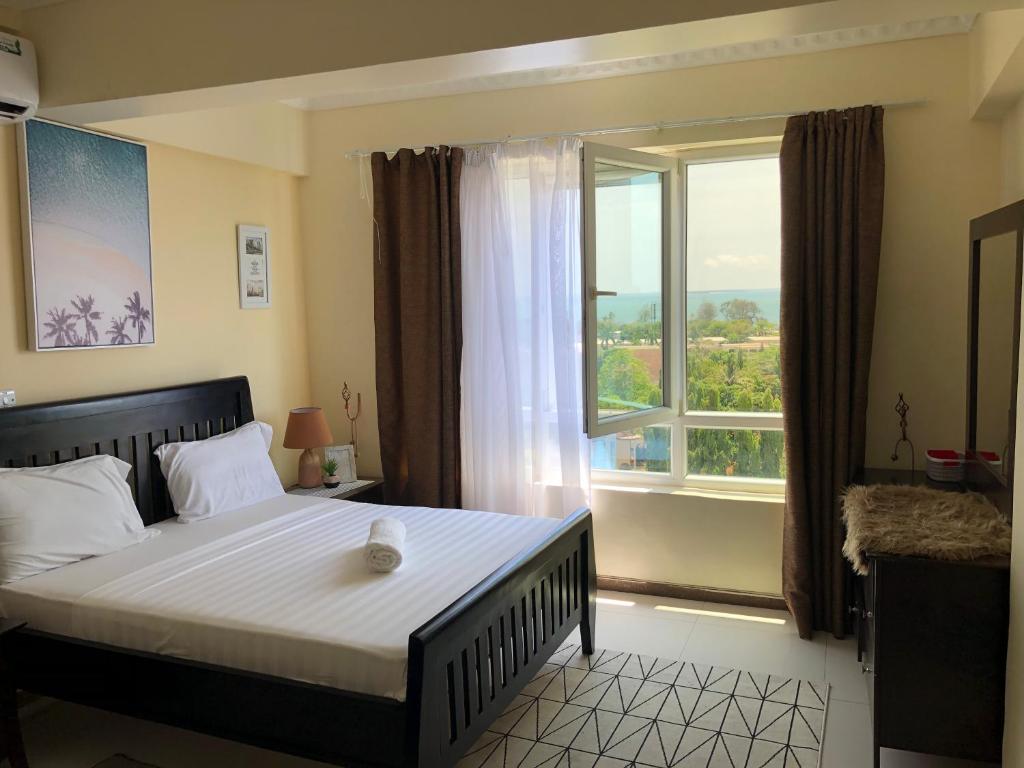 a bedroom with a bed with a large window at The Penthouse oysterbay in Dar es Salaam