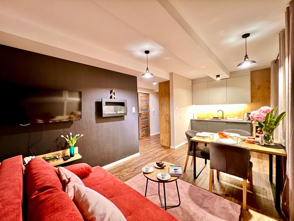 un soggiorno con divano rosso e una cucina di Apartament SPA 04 Resort Kozubnik blisko Szczyrk - 5D Apartamenty a Porąbka
