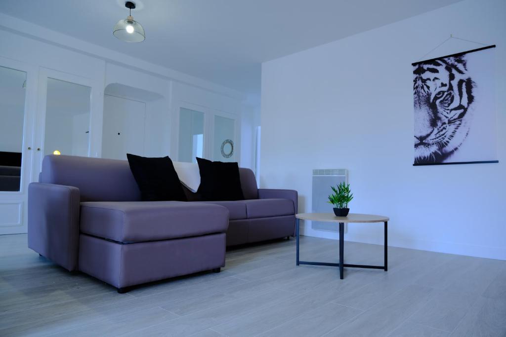 a living room with a purple couch and a table at CALYPSO- Grand T3 - Arrivée Autonome - Parking & Wifi gratuit in Melun