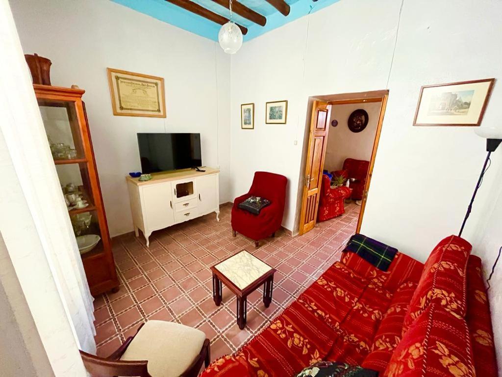 sala de estar con sofá rojo y TV en Casa Béjar, Tranquila casa con chimenea, patios, junto a la piscina, en Cañete la Real