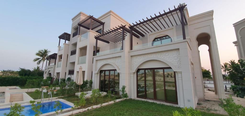 a large white building with a pool in front of it at Forest Island apartment in Salalah in Salalah