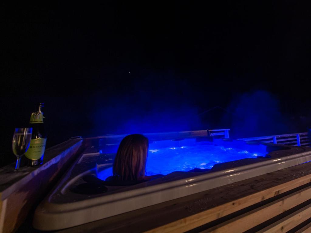 uma mulher sentada numa banheira de hidromassagem com luzes azuis em Arctic Lodge Tromvik with jacuzzi em Tromsø
