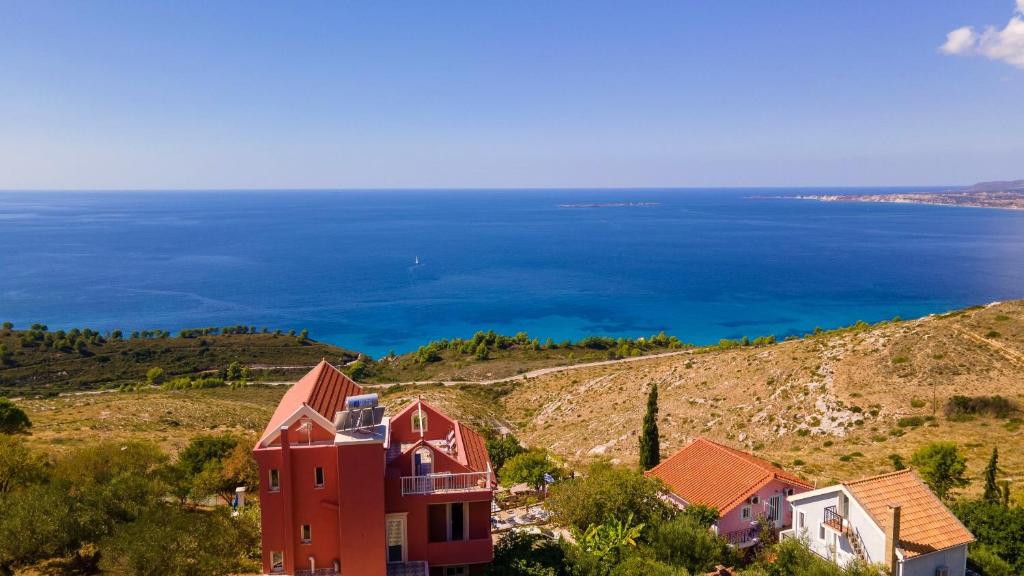 a red house on a hill next to the ocean at Aeolos Studios Kefalonia in Khelmáta