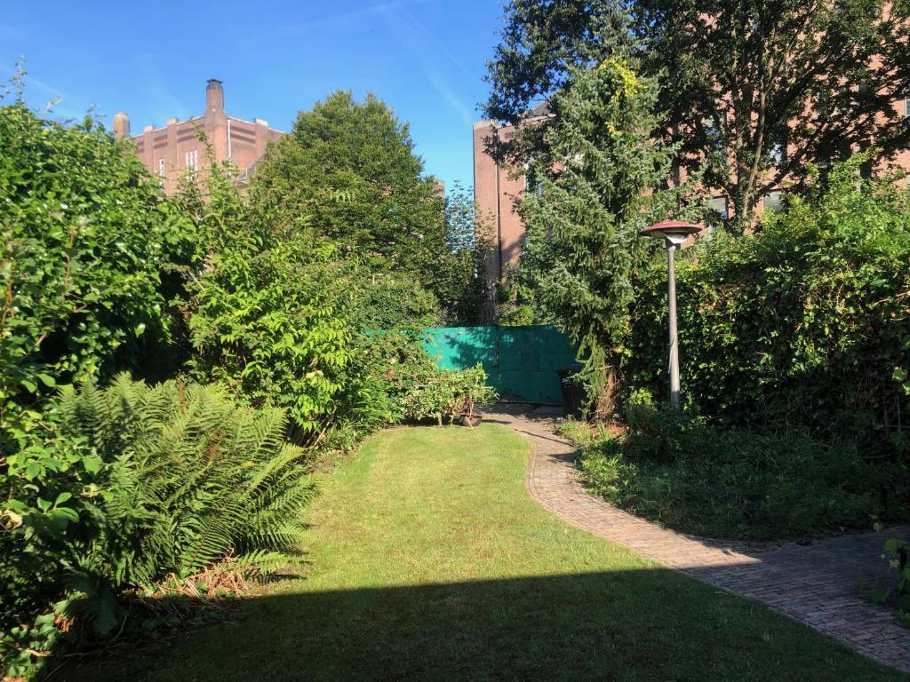 een tuin met groen gras en bomen en een pad bij Big appartment in sunny privat garden in Nijmegen