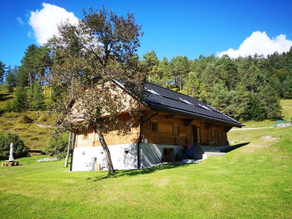 a wooden barn with a tree in a field at Valle Divina in Mislinja