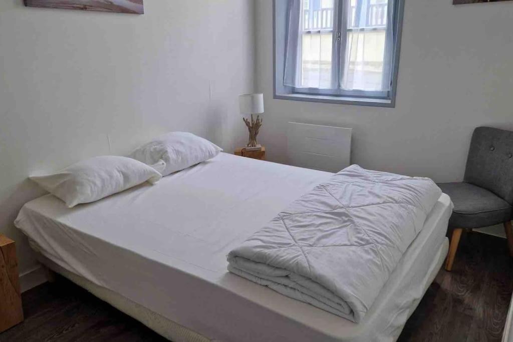 1 dormitorio con 1 cama, 1 silla y 1 ventana en LE CLOS DE BEAUCHAMP APPARTEMENT Le BORD DE MER 2 vélos sont disponibles gratuitement, en Saint-Valery-sur-Somme