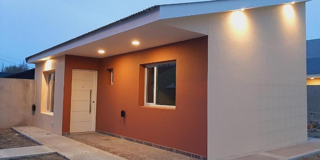 una pequeña casa con una pared de color naranja y una puerta blanca en Apart HAMU en El Calafate