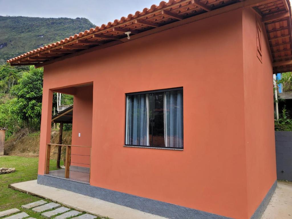 a side view of a small orange house with a window at Casa do Ipê - Hospedagem in Lumiar