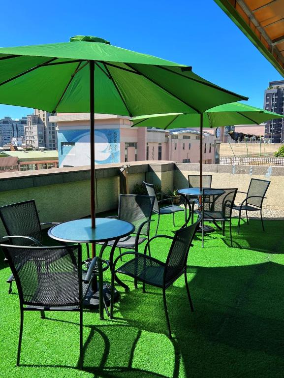 a group of tables and chairs with green umbrellas at Link World Hotel in Taipei