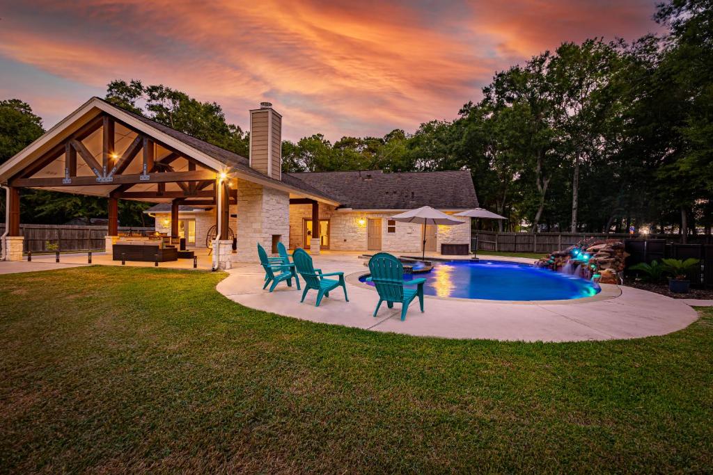 un patio trasero con piscina y sillas y una casa en 2 King Suites with Private Pool and Spa, Texas-Sized Covered Patio and Outdoor Kitchen and BBQ, en Tomball