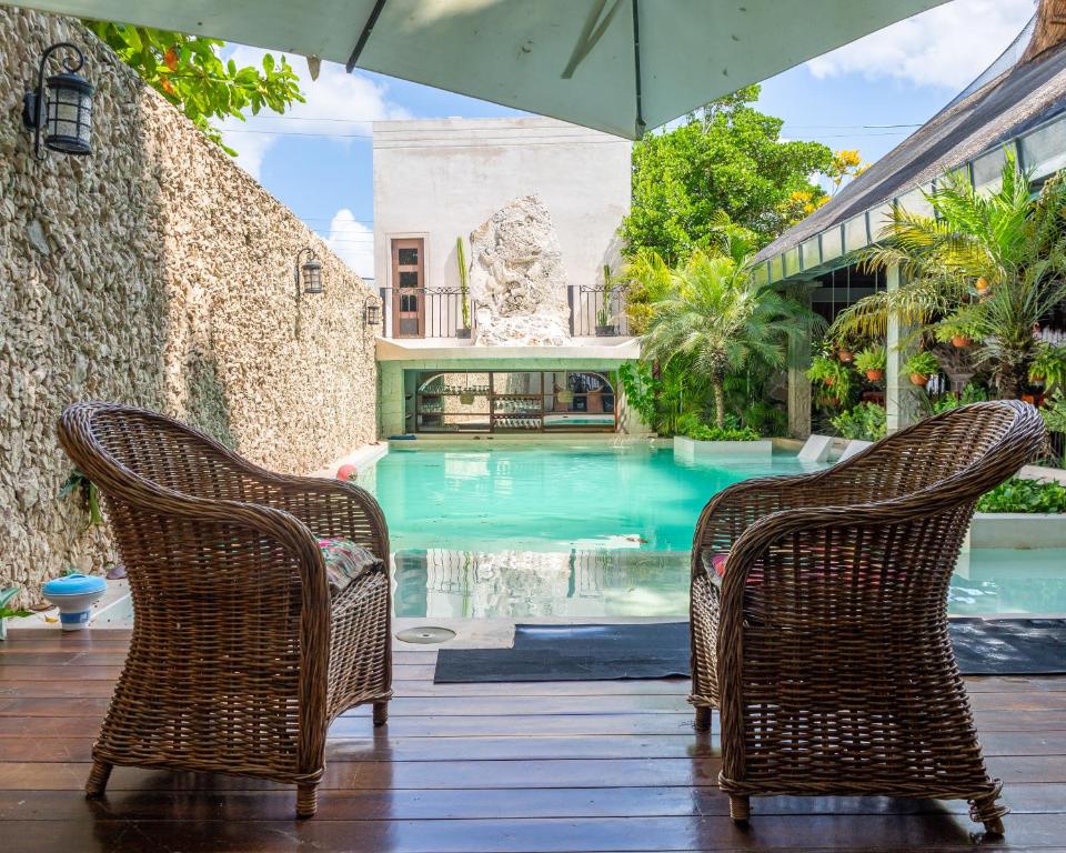 zwei Stühle und ein Sonnenschirm neben einem Pool in der Unterkunft Hotel Nojoch che in Cobá