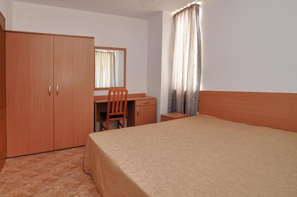 a bedroom with a bed and a desk and a chair at Panorama Krim Beach Apartment in Ravda