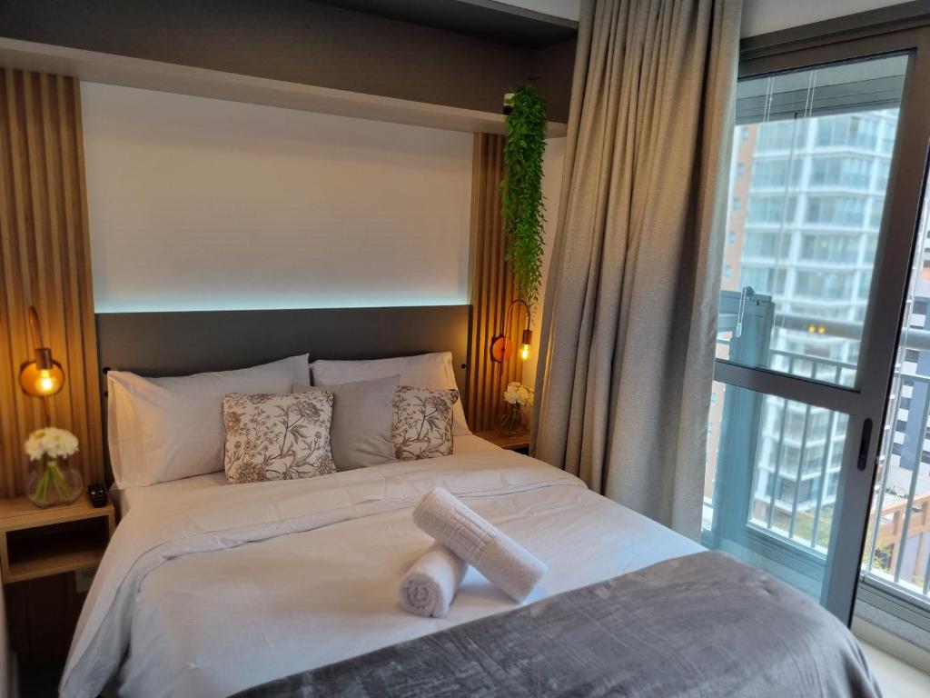 a bedroom with a large bed and a large window at Vista do parque Ibirapuera do lado do Metrô in Sao Paulo