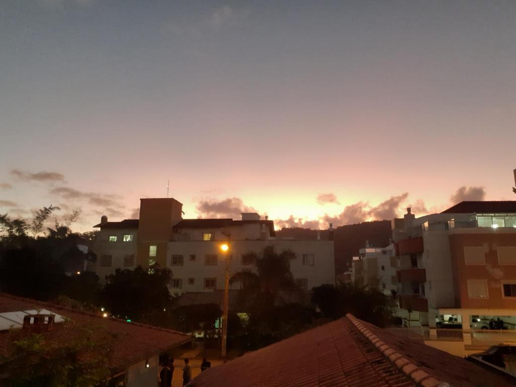 una puesta de sol en una ciudad con edificios y una luz de la calle en Apartamento Encantador 250 metros do mar!, en Florianópolis