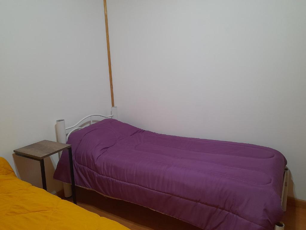a bed with purple sheets in a room at Cabaña Bellavista sur in Comodoro Rivadavia
