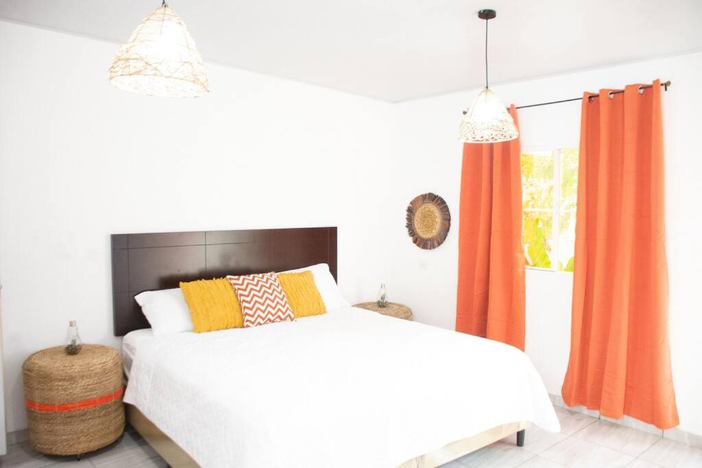 a bedroom with a white bed and orange curtains at Habitacion Fuego - Villa Valle Campo 