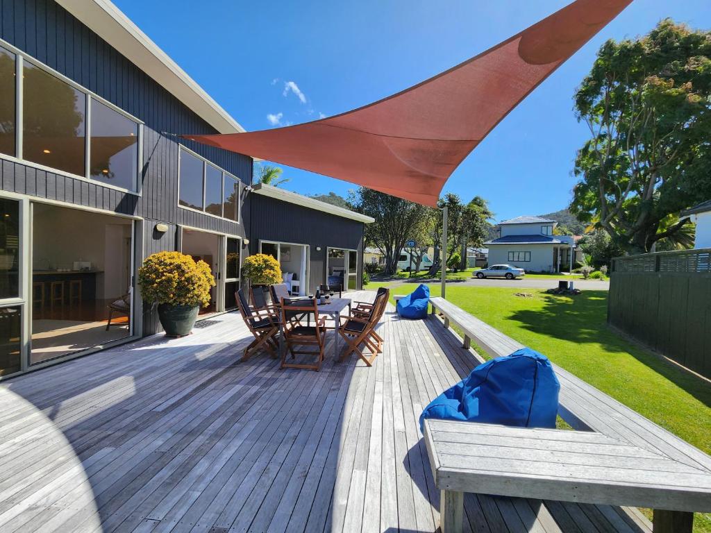 eine Holzterrasse mit einem Tisch und Stühlen auf einem Haus in der Unterkunft Easy Days Hahei in Hahei