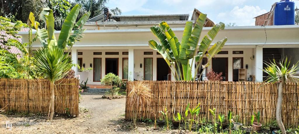 a fence in front of a house with palm trees at Ebucu in Kuta Lombok