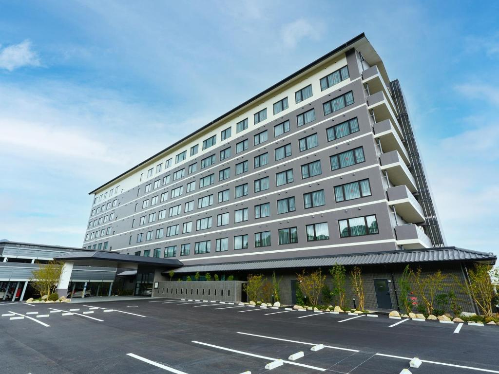 un gran edificio con un estacionamiento delante de él en Grandvrio Hotel Beppuwan Wakura - ROUTE INN HOTELS - en Beppu