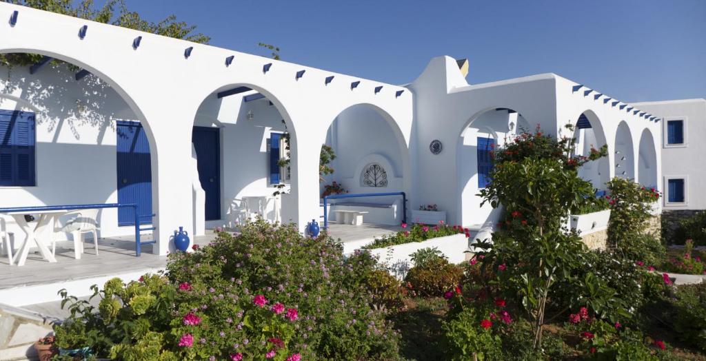 ein weißes Gebäude mit Bögen und Blumen in der Unterkunft Bungalows Marina in Naoussa