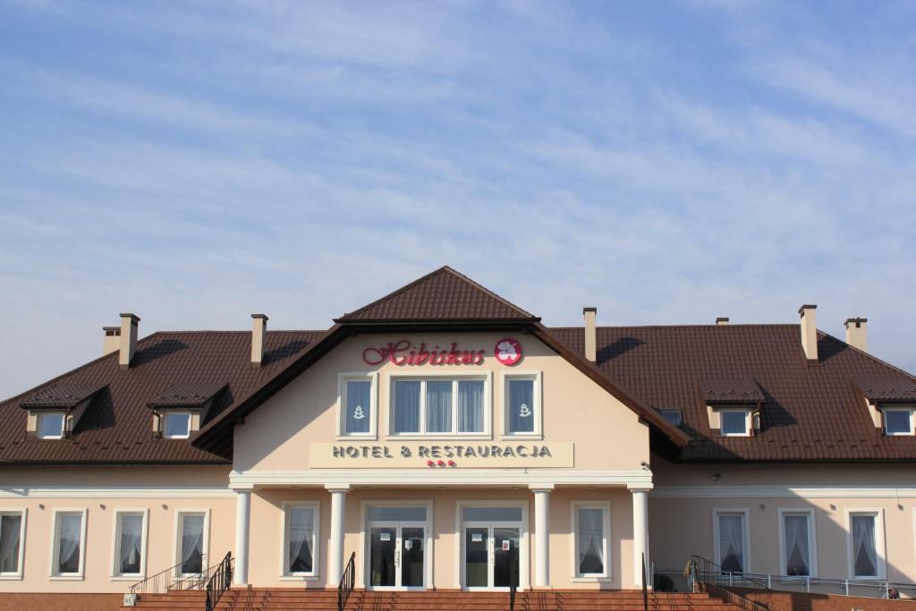 a large white building with a roof at Hotel Hibiskus in Boguchwała