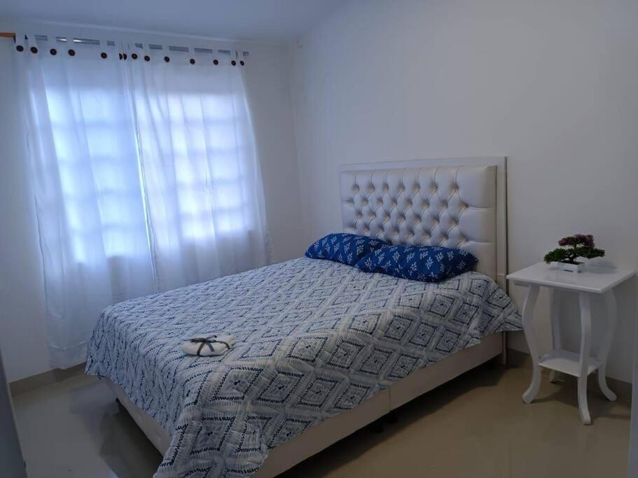 sypialnia z łóżkiem z niebieską kołdrą i oknem w obiekcie Apartamento Roldanillo pueblo mágico w mieście Roldanillo