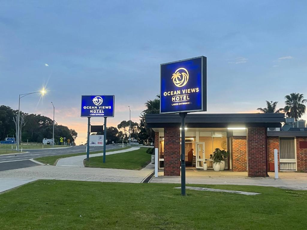 a sign for a green hawk hotel next to a road at Ocean Views Motel Lakes Entrance in Lakes Entrance