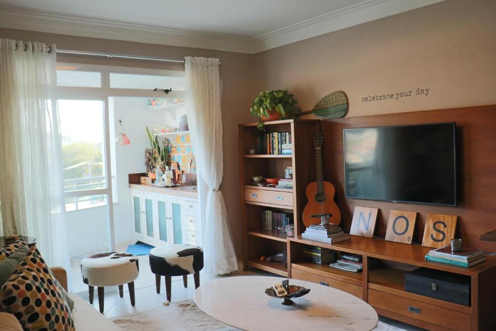 sala de estar con TV de pantalla plana y mesa en Apartamento aconchegante em Floripa - caminho das praias, en Florianópolis