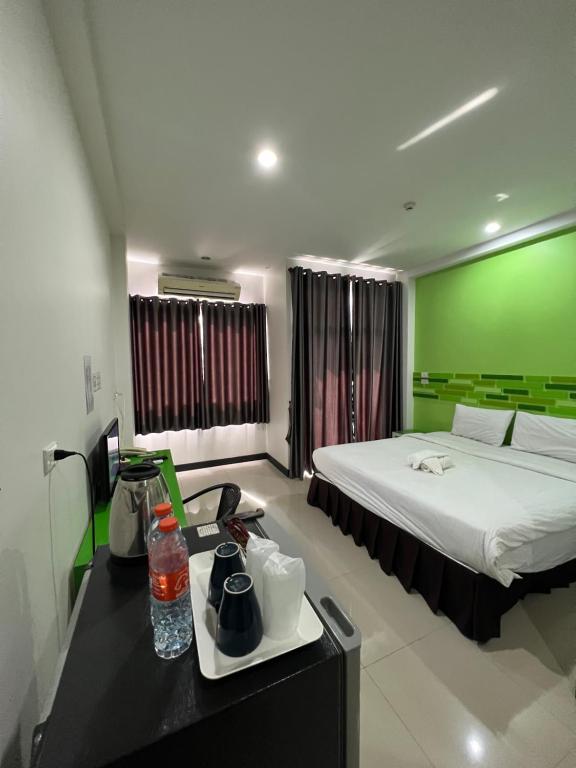 Habitación de hotel con cama y pared verde en โรงแรมช้างใหญ่ใจดี, en Yasothon