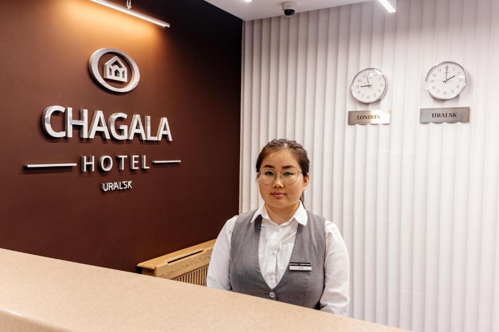 a woman standing next to a counter in a hotel at Chagala Hotel Uralsk in Uralsk