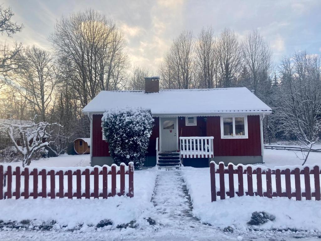 czerwony dom z płotem w śniegu w obiekcie TROLLEBO günstig gelegene renovierte Stuga mit Sauna und 250 Mbs Glasfaser w mieście Eriksmåla