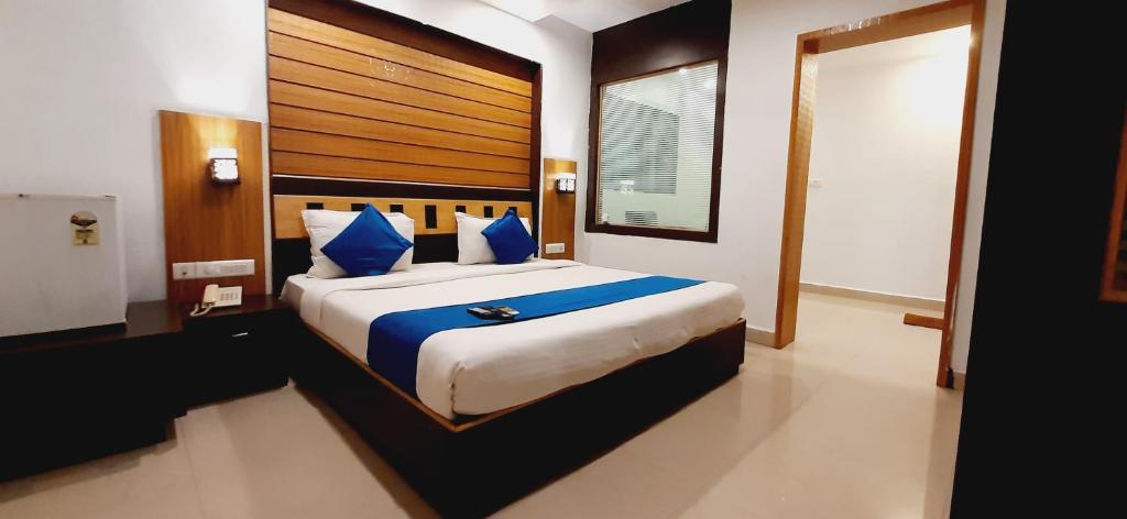 a bedroom with a large bed with blue pillows at Hotel Kosala Vijayawada in Vijayawāda