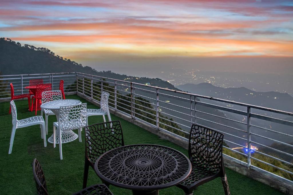 a group of tables and chairs sitting on a balcony at Aravindam House I Open Rooftop & Garden I Bonfire I By Vanasthali Kasauli in Kasauli