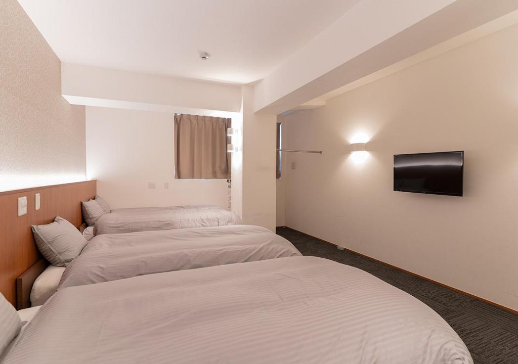 Habitación de hotel con 2 camas y TV en COCOSHUKU Nakano, en Tokio