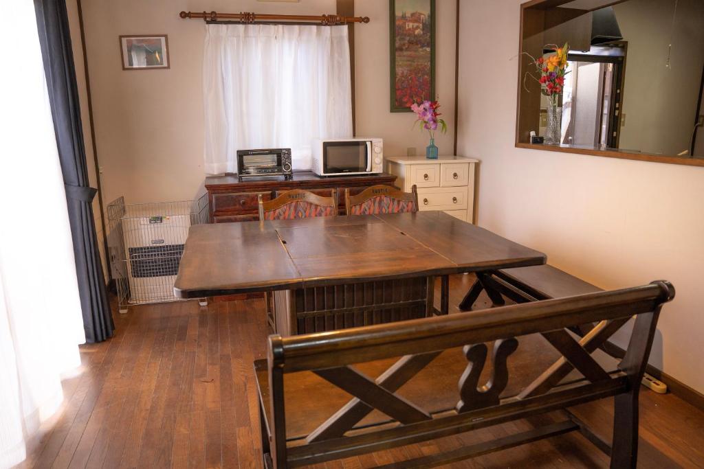 een houten tafel met een bank in een kamer bij 一組貸切宿 岡村 弐番館 一棟まるまる貸切 in Suwa