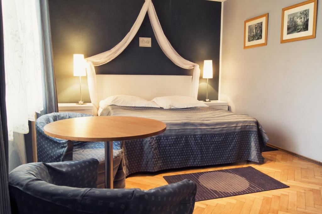 カルパチにあるHomestay Willa Annaのベッド、テーブル、椅子が備わるホテルルームです。