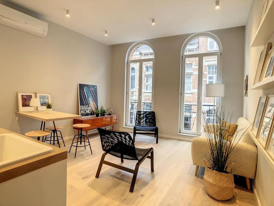 ein Wohnzimmer mit Stühlen, einem Tisch und Fenstern in der Unterkunft Nieuw appartement in Leuven centrum! in Löwen