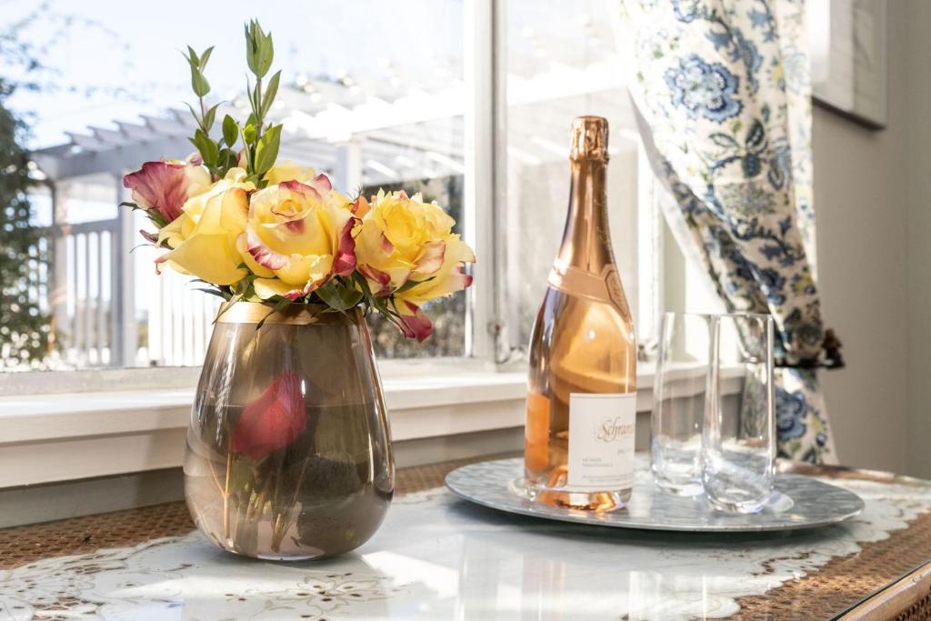 a bottle of champagne and a vase of flowers on a table at Charming Garden Cottage- steps to historic Old Town Half Moon Bay in Half Moon Bay
