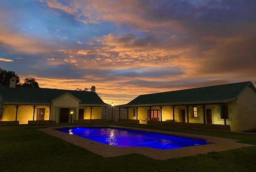 une maison avec une piscine bleue dans la cour dans l'établissement Trumpetters Drift Game Farm, à Grahamstown