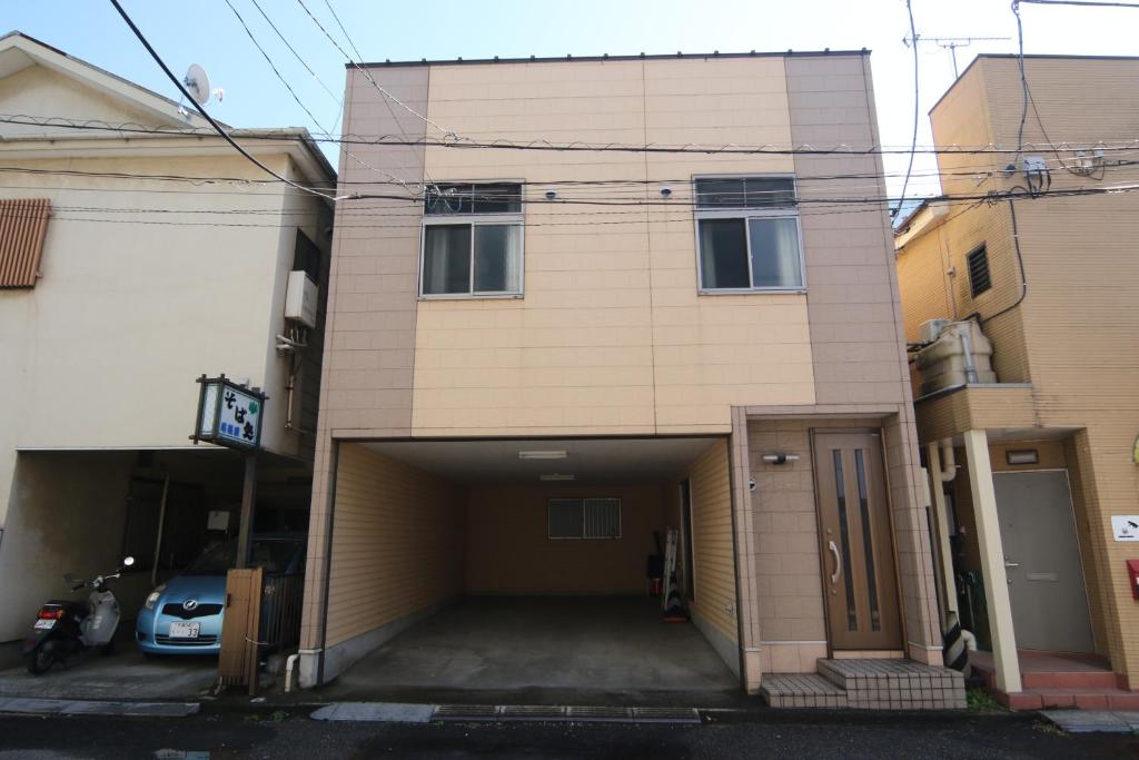 ein Gebäude mit einer Garage mit einem Parkplatz in der Unterkunft プチバスケット in Chiba