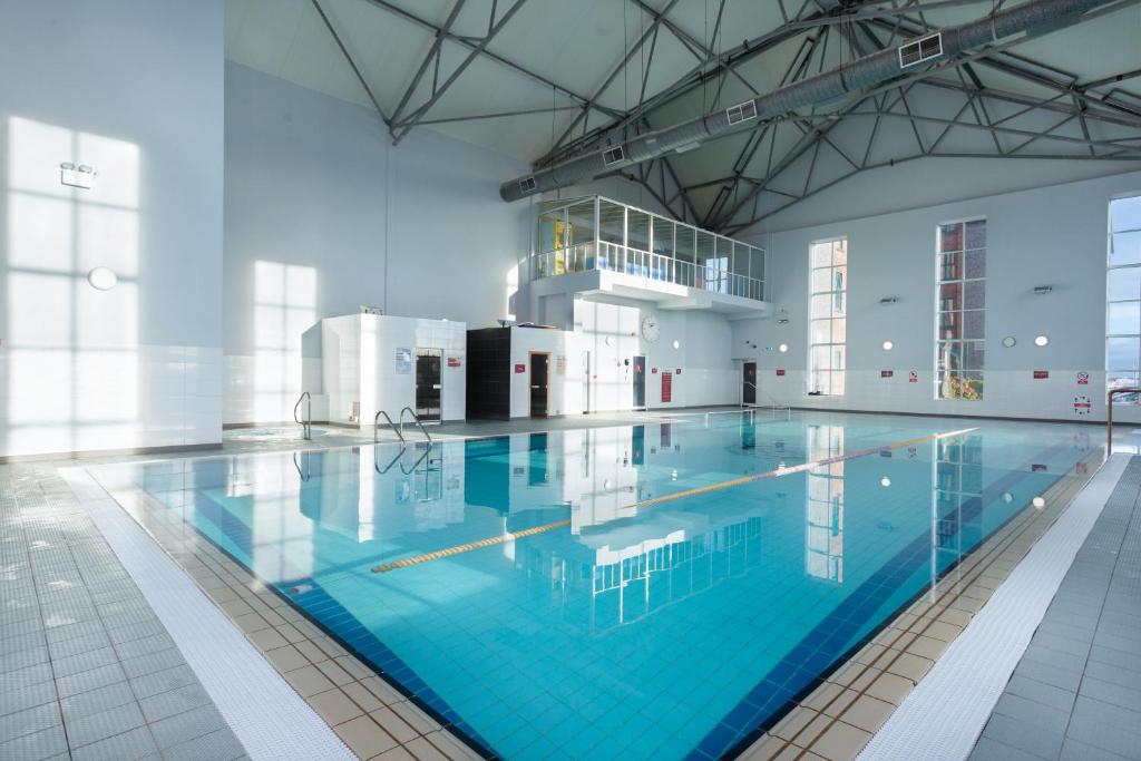 - une grande piscine d'eau bleue dans un bâtiment dans l'établissement Maldron Hotel & Leisure Centre, Oranmore Galway, à Oranmore