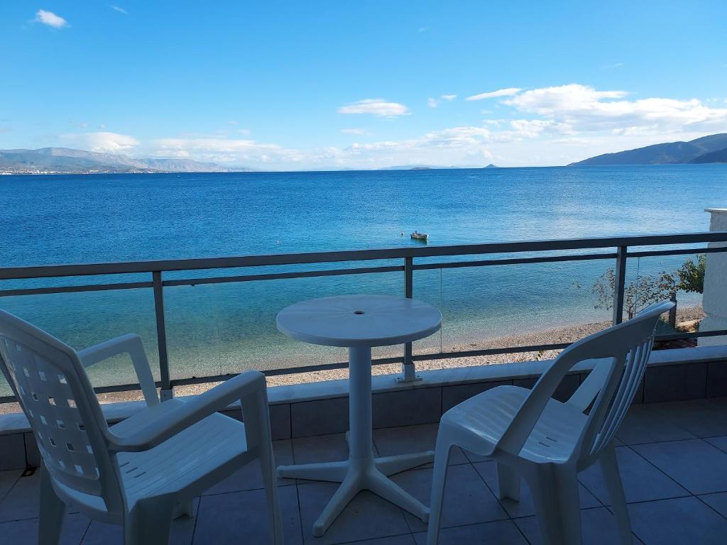 Aqua Apartments في لوترا أوراياس إلينيس: طاولة وكراسي على شرفة مطلة على المحيط
