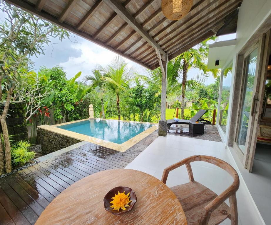 a patio with a table and a swimming pool at Pinggala Villa Ubud in Tegalalang