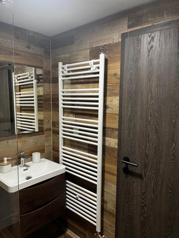 ein Badezimmer mit einem Waschbecken und einer Holzwand in der Unterkunft Vila Bašić Vlašić Apartman VUK in Vlasic