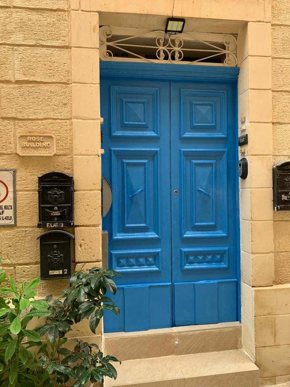 una puerta azul en el lateral de un edificio en Rose Building Apartment, en Cospicua